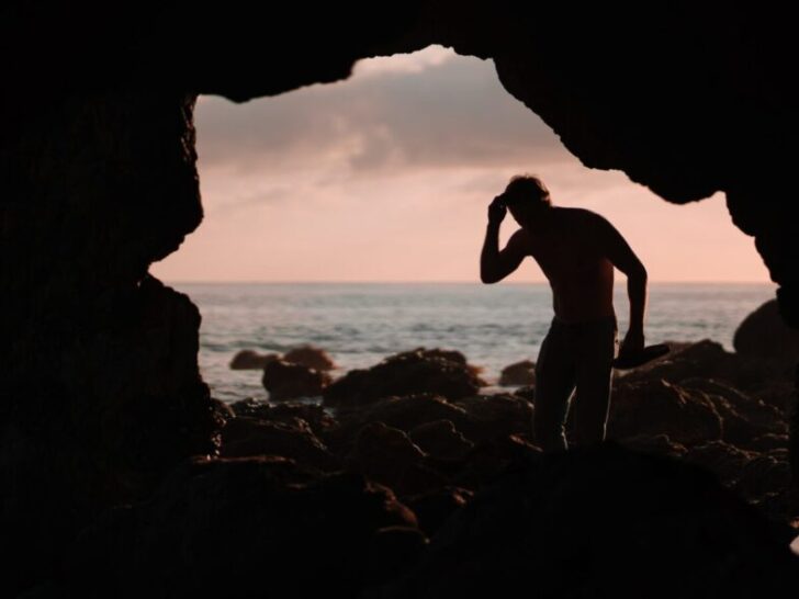Guy Standing In Cave Near Ocean
