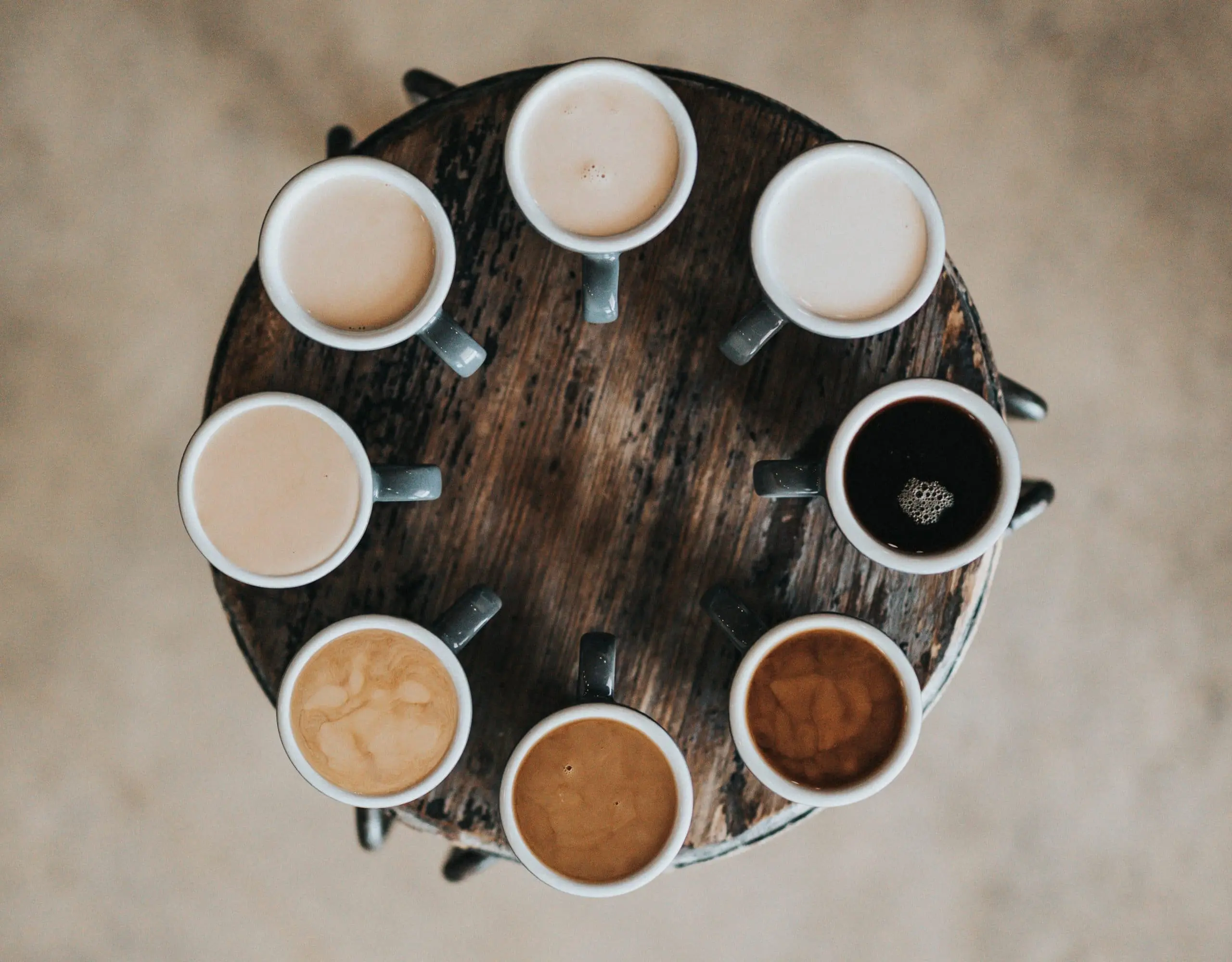 flat lay photography of eight coffee latte in mugs on round table