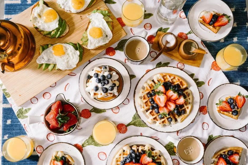Multiple breakfast options including fried eggs, waffles, coffee, orange juice, fruit.
