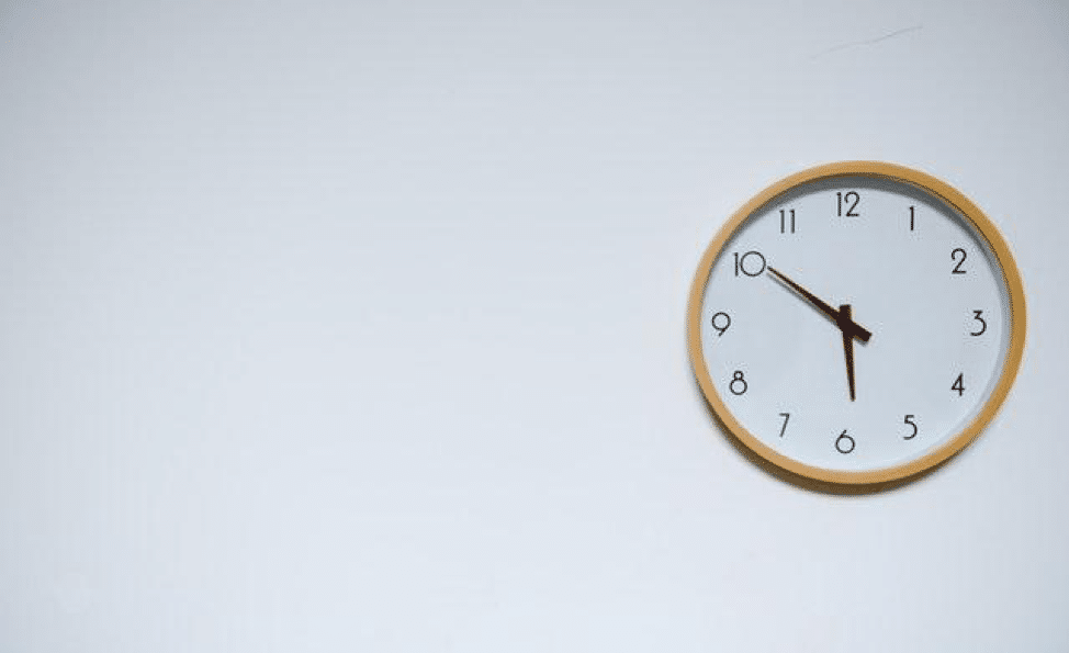 Clock with golden frame on white wall.