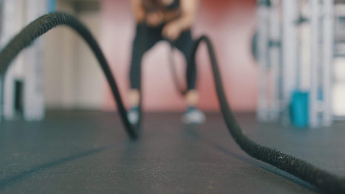 Person using black battle ropes for exercise.