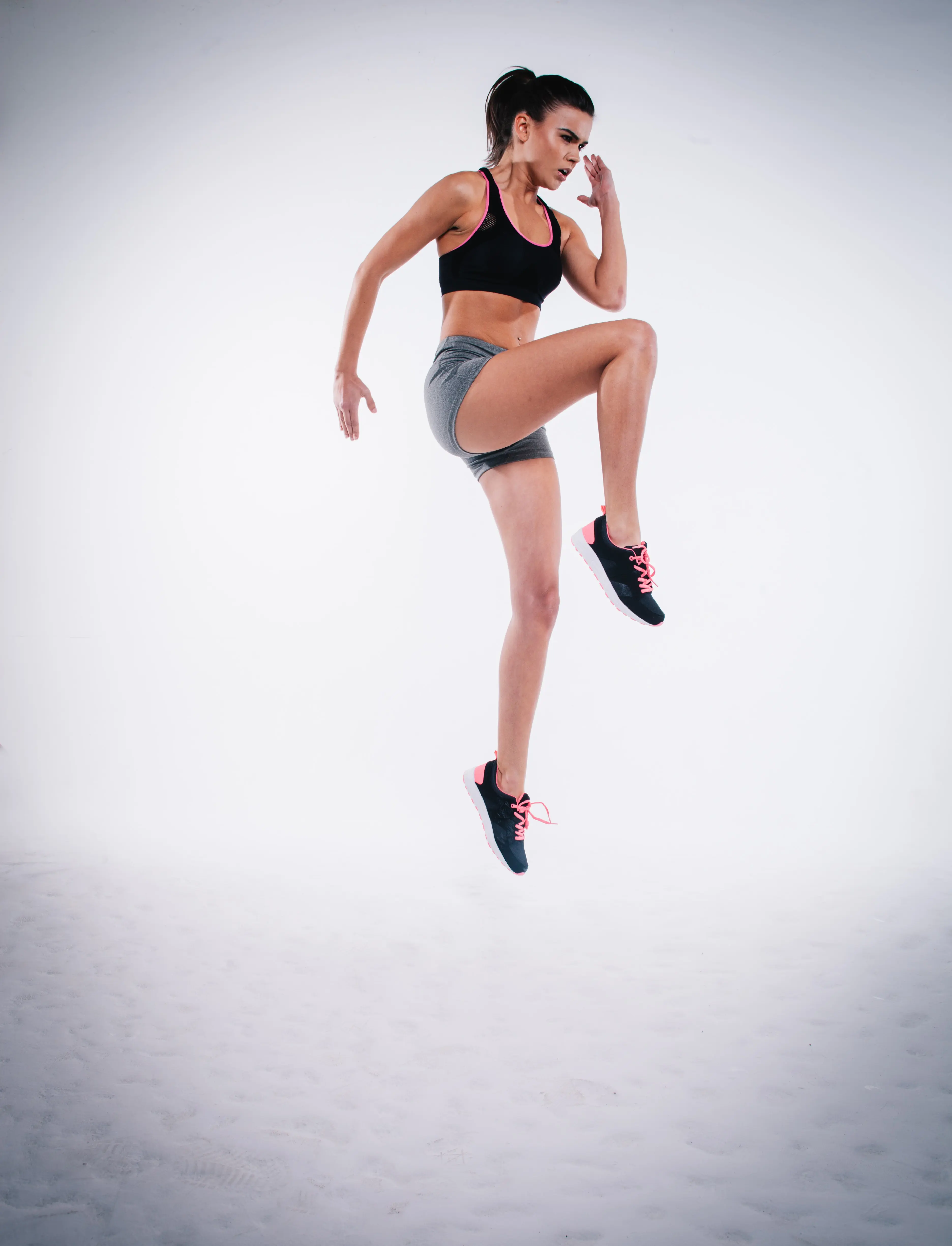 Woman doing a jump lunge in front of a white wall