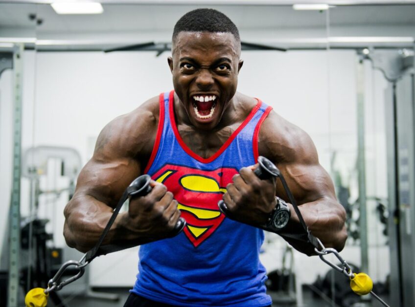 Guy in Superman Tank Top flexing muscles while working out.