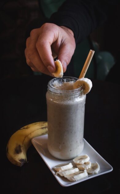Person holding slice of banana over milk oats.