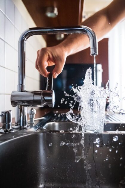 Man overfilling glass cup with water