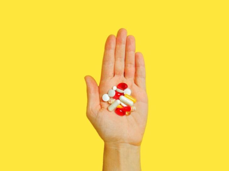 Hand holding pills on a yellow background