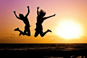 Two Women Jumping with Sunset Behind Them