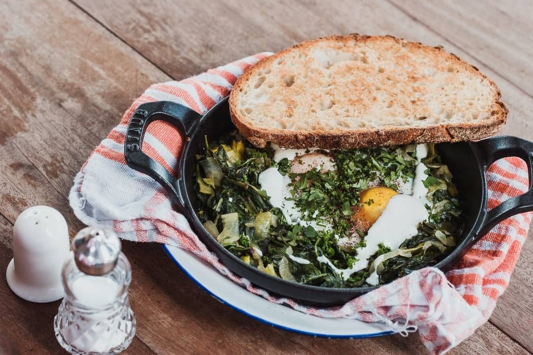 A sklillet with eggs and a Spinach bake, as featured on a blog about healthy eating hacks
