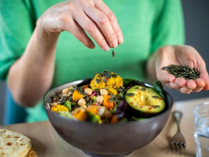 A woman sprinkling spices onto salad, as featured on a blog about healthy eating hacks