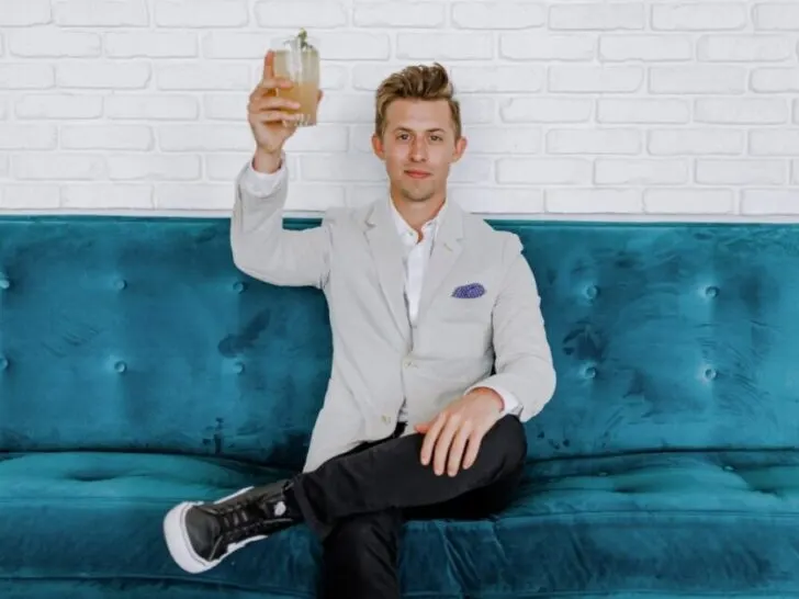 Man in White Blazer Raising Glass on Blue Couch