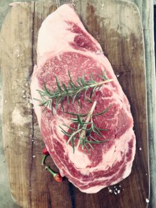 Large Uncooked Steak Salted on Cutting Board