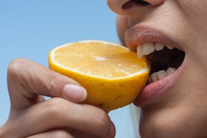 Person Taking Bite Out of Lemon