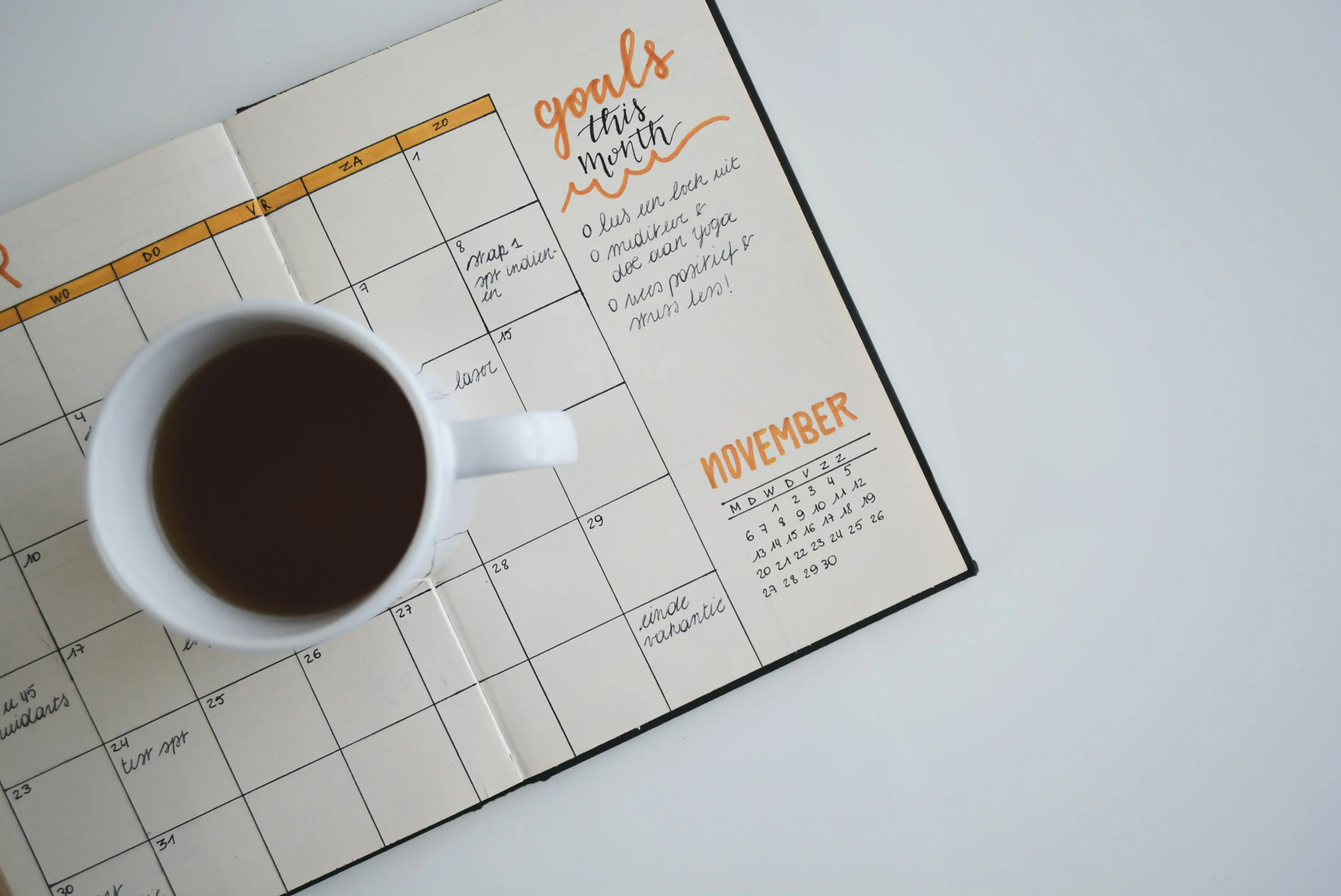White Ceramic Mug of Coffee on Top of Day Planner