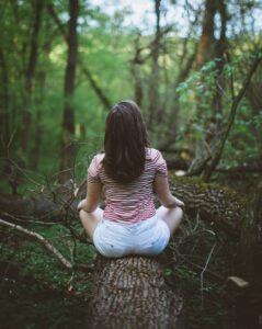 Woman Sitting on Tree Log in Woods