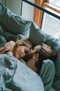 Man Kissing Woman's Forehead In Bed