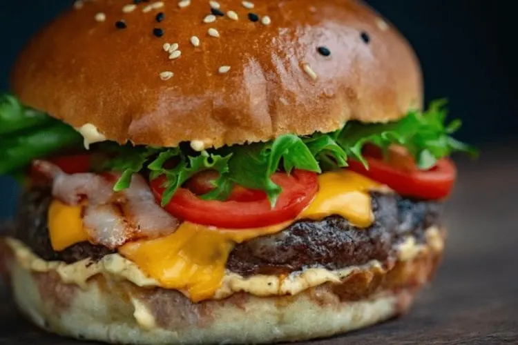 Juicy cheeseburger on bun with lettuce, tomato and onion.