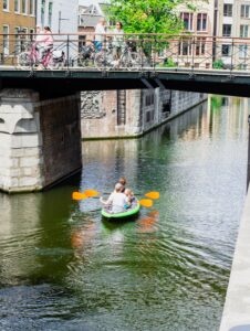 Two People Kayaking Under Bridge