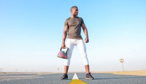 Guy Holding Kettlebell In Middle of Street