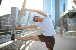 Guy Stretching on Railing With Cityscape In Background