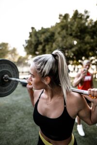 Woman with Barbell on Back in Park In Morning