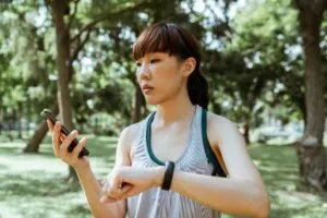 Woman Looking At Smart Phone and Fitness Band