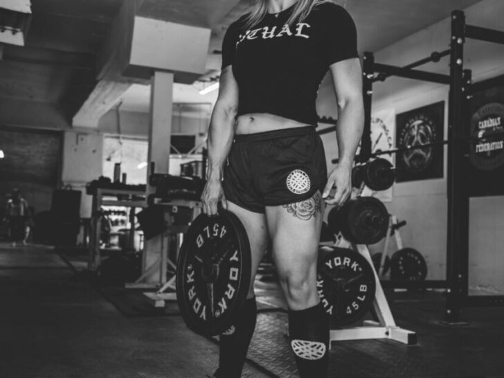 Woman in Gym with Strong Quads Holding Weight Plate in Black and White Photo