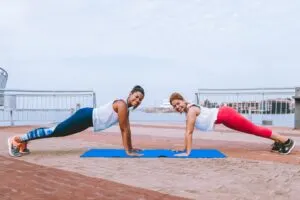 Two Woman in High Plank Position Facing Each Other Smiling