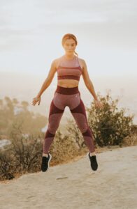Woman Jumping in the Air on Trail With Sun Behind