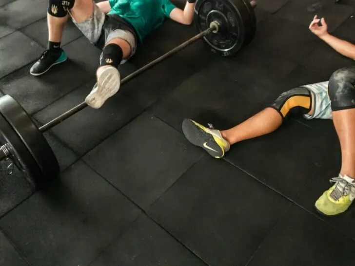 Two Athletes Laying on Floor Exhausted From Workout