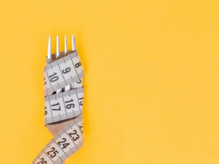 Fork Wrapped in Measuring Tape on Yellow Background