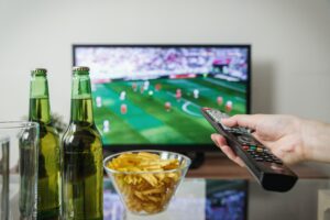 Hand Holding Remote Watching Television with Beer and Chips