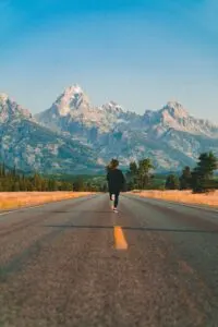 Woman Running Down Road Without Headphones Mountain In Front