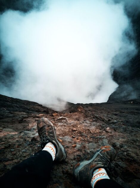 Runner Sitting at Edge of Mountain with Smoke Coming Up