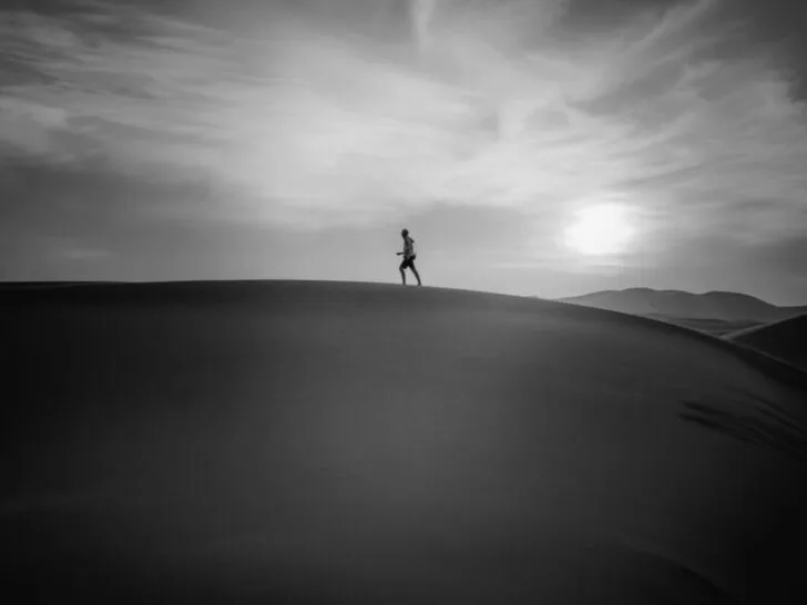 Black and White Photo of Distant Runner on Ridgeline with Sun Setting in the background