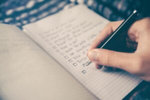 Woman writing goals in journal with pen.