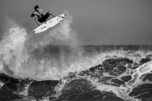 Surfer jumping high off a wave in black and white photograph using flow state