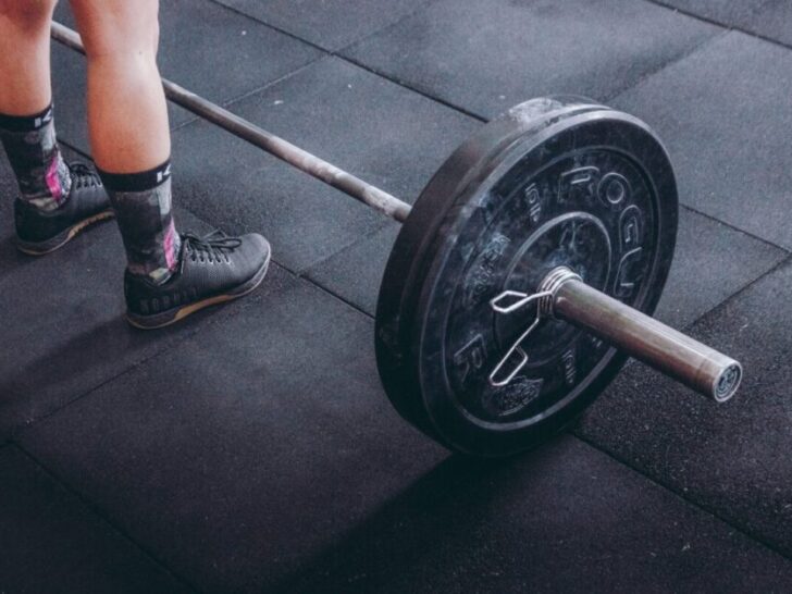 Guy standing in front of barbell with weight loaded on one side.