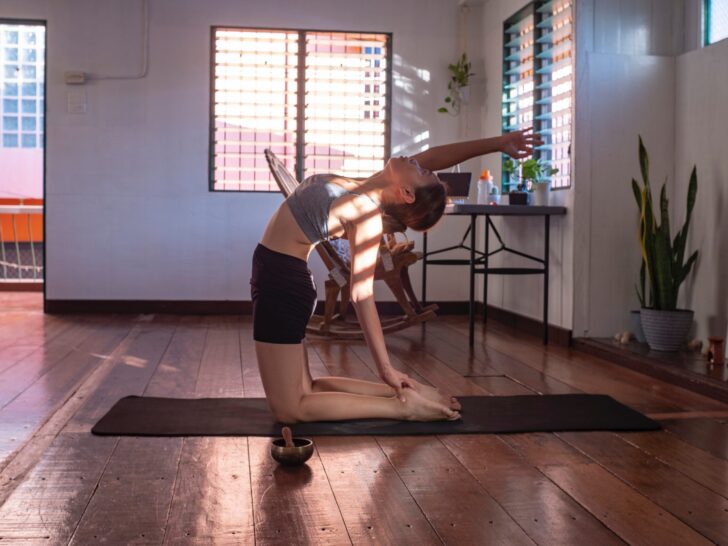 Woman stretching in her apartment on yoga mat.