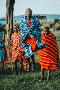 Maasai warriors in bright clothes doing traditional jump dance.