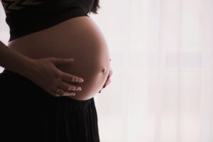 Woman with exposed pregnant belly holding with her hands